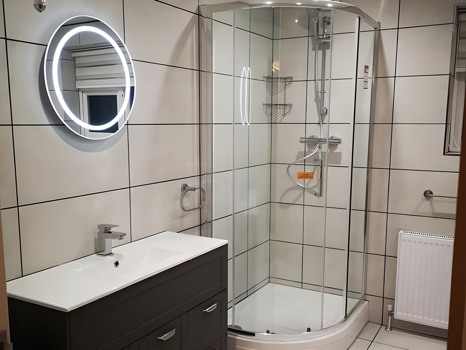 Completed bathroom with tiled walls, shower enclosure, vanity unit and lit mirror